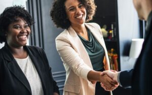 Smiling business women shake hands with business man